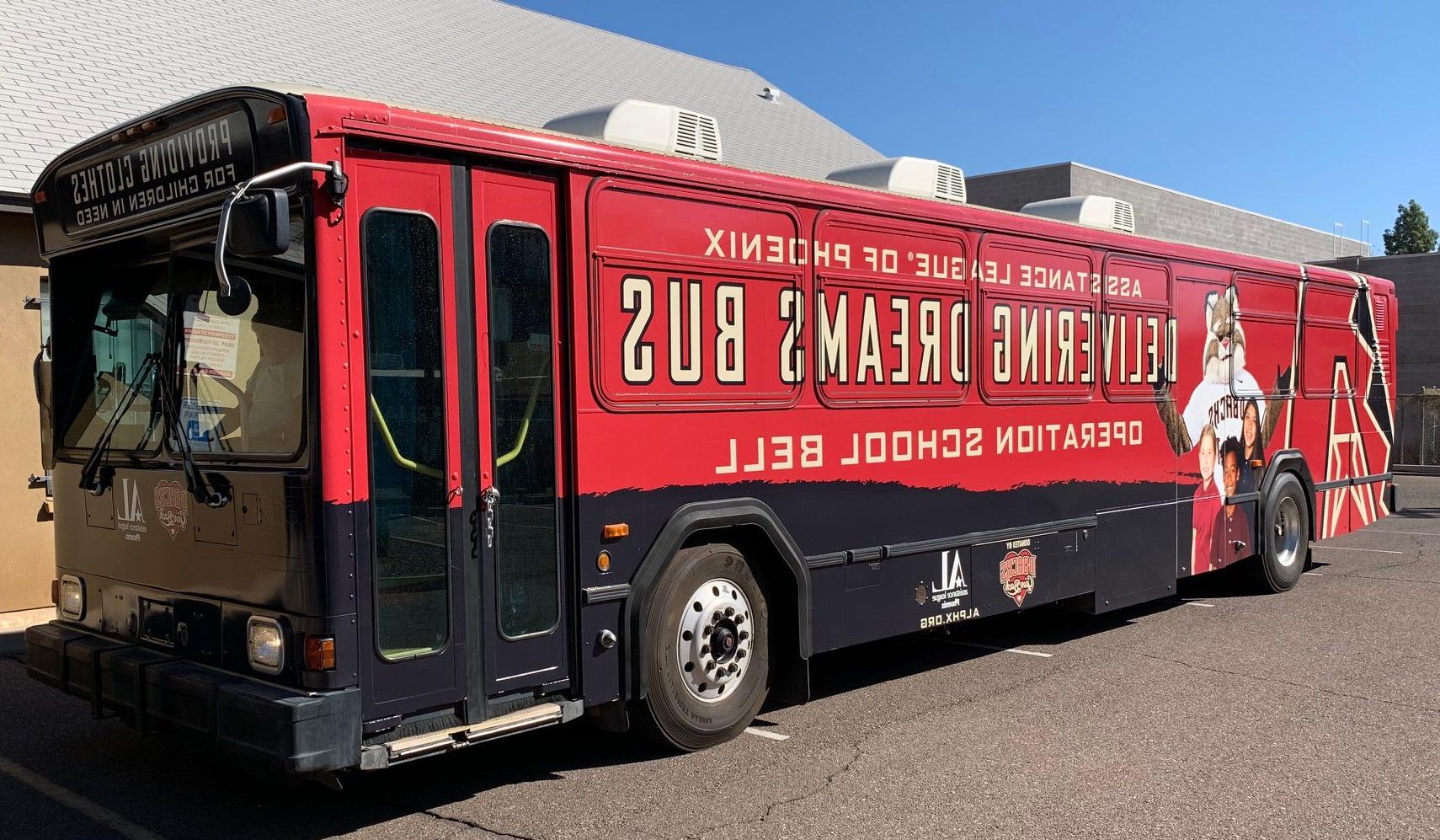 Red and black bus wrapped with Assistance League of Phoenix, Diamond Backs mascot, school kids, and Delivering Dreams Bus.